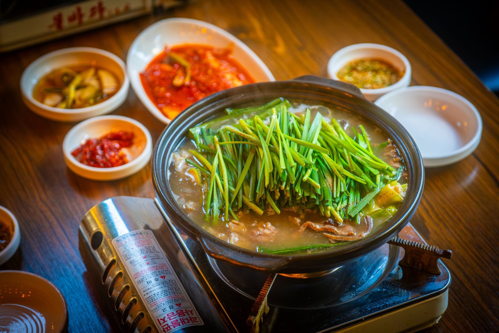 Warm Korean beef broth hotpot served with fresh chives and homemade kimchi, enjoyed at Minjeong Restaurant in Seongsu on a cozy afternoon.